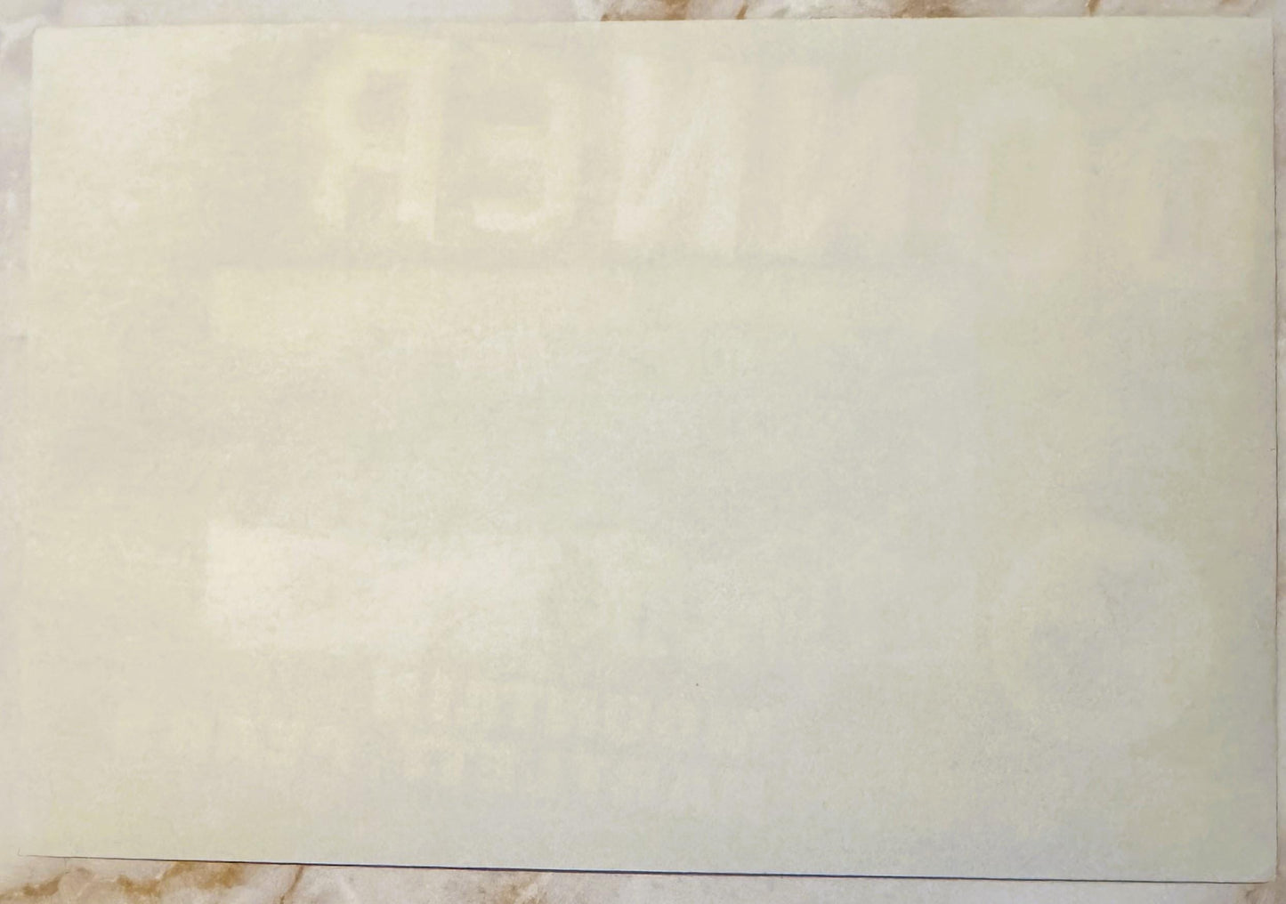 Cream-colored vintage fruit crate label with faint printed text, photographed flat against a neutral surface