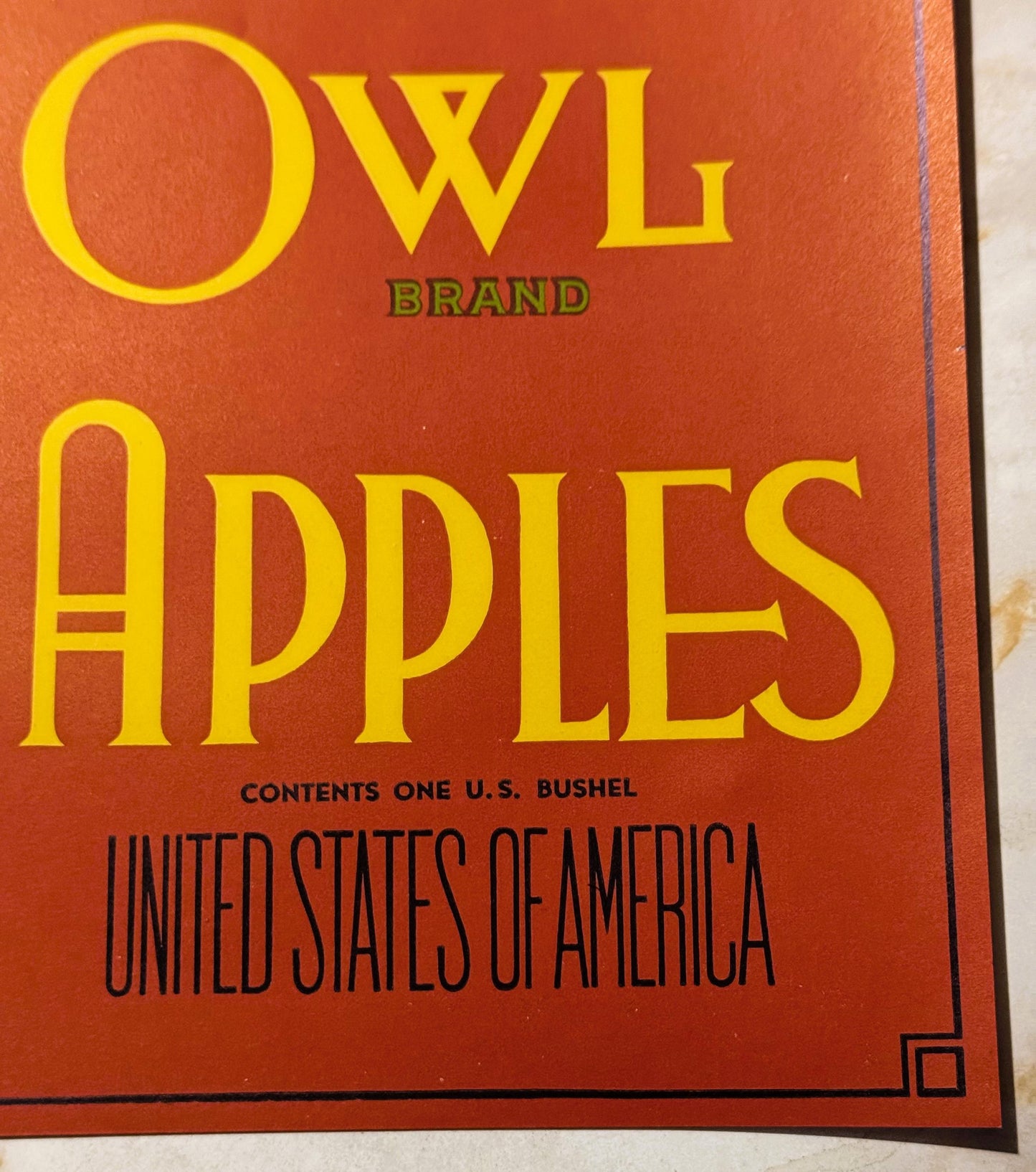 Antique Owl Brand Apples crate label with yellow text on red-orange background, listing one U.S. bushel contents and United S