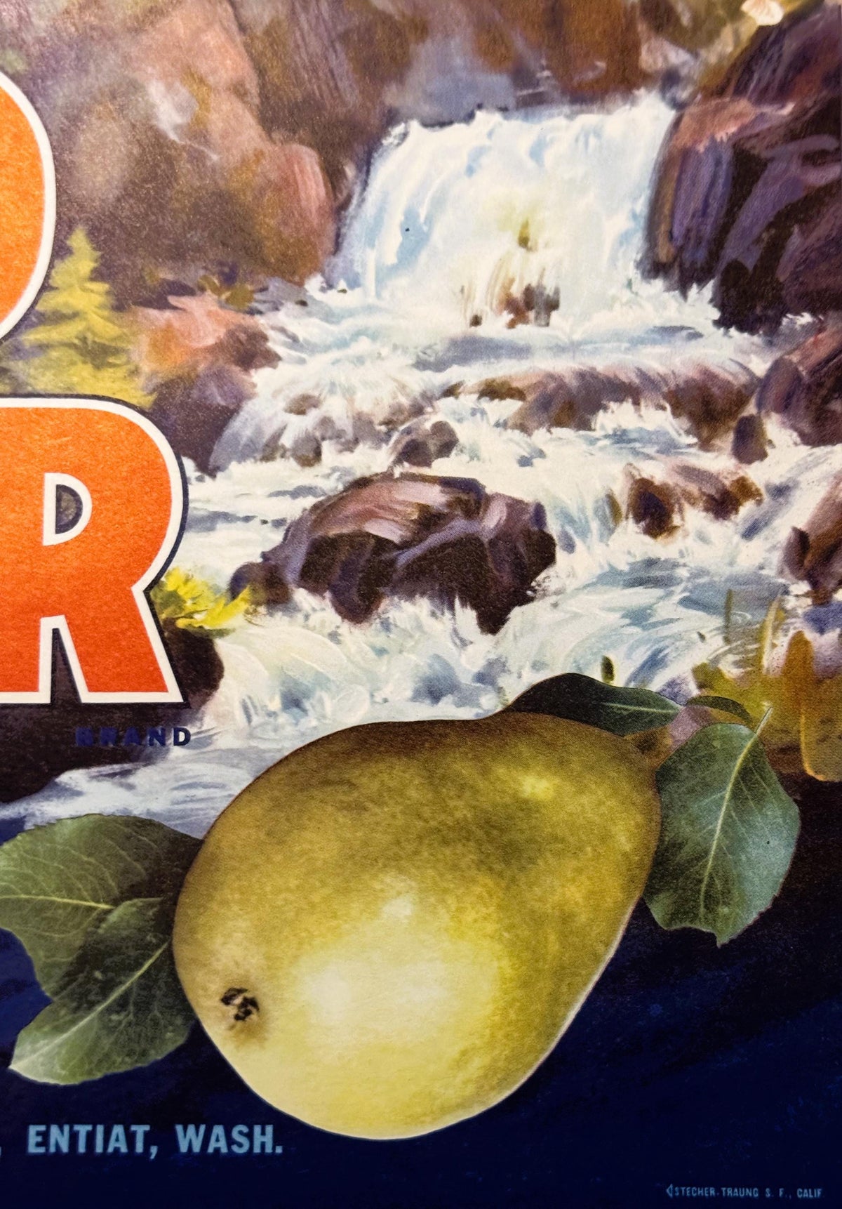 Vintage pear crate label featuring a yellow pear with leaves, waterfall landscape, orange "R" logo, and "Entiat, Wash." text 