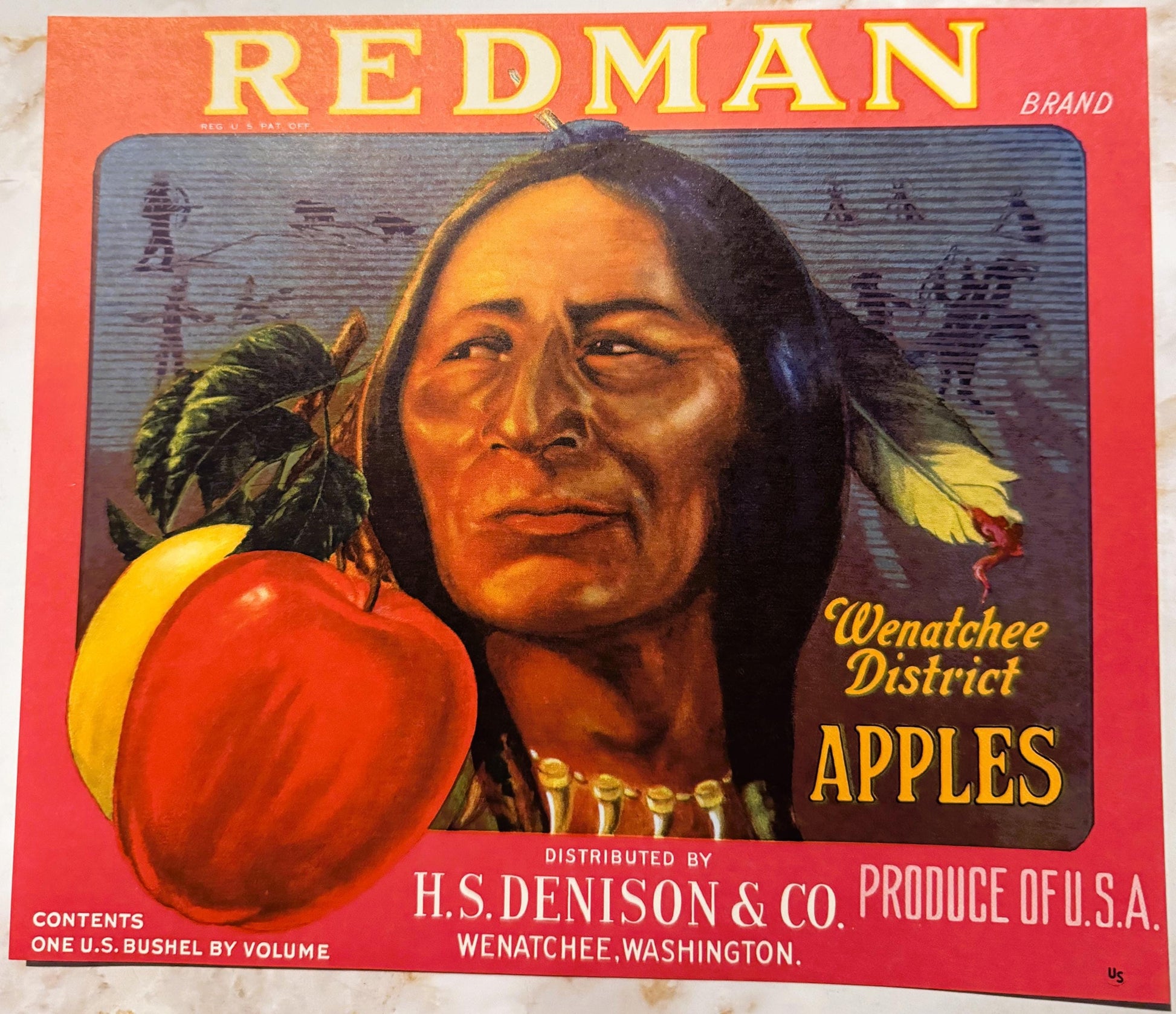 Vintage Redman Brand apple crate label featuring a Native American man with long dark hair and feathers, holding red apples a