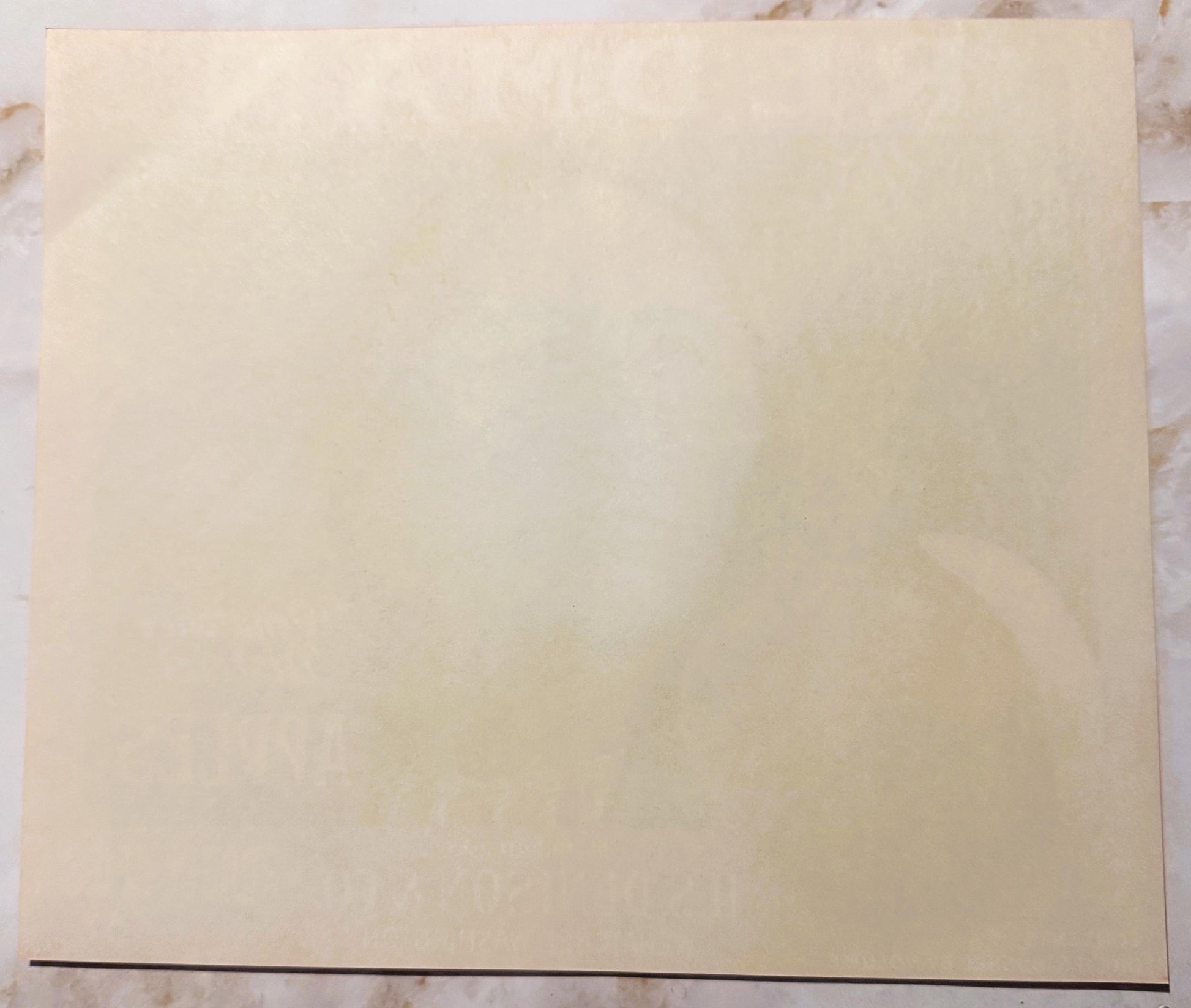 Blank cream-colored vintage apple crate label on marble surface with dark line at bottom edge