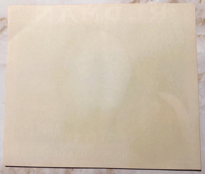 Blank cream-colored vintage apple crate label on marble surface with dark line at bottom edge