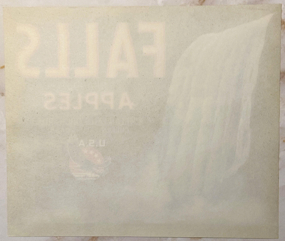 Faded vintage apple crate label with embossed text on cream-colored paper, showing watermarked design and partial lettering