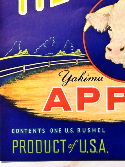 Vintage Yakima apple crate label featuring a white cow's head in profile against a blue night sky landscape with fenced pastu
