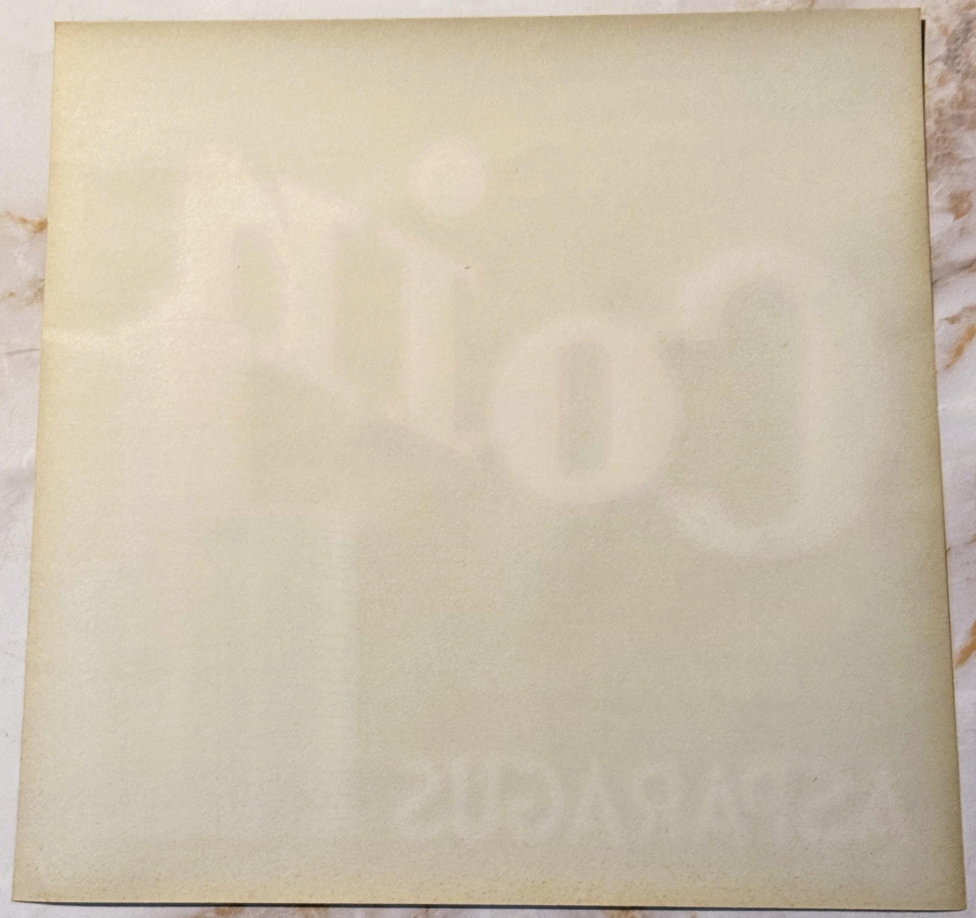 Blank cream-colored vintage crate label with faint watermark text, photographed flat on marble surface