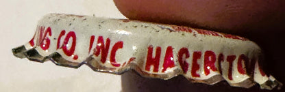 Close-up of vintage bottle cap with red text reading "NESBITT'S" and "HAGERSTOWN" on cream-colored ridged surface, held by ha