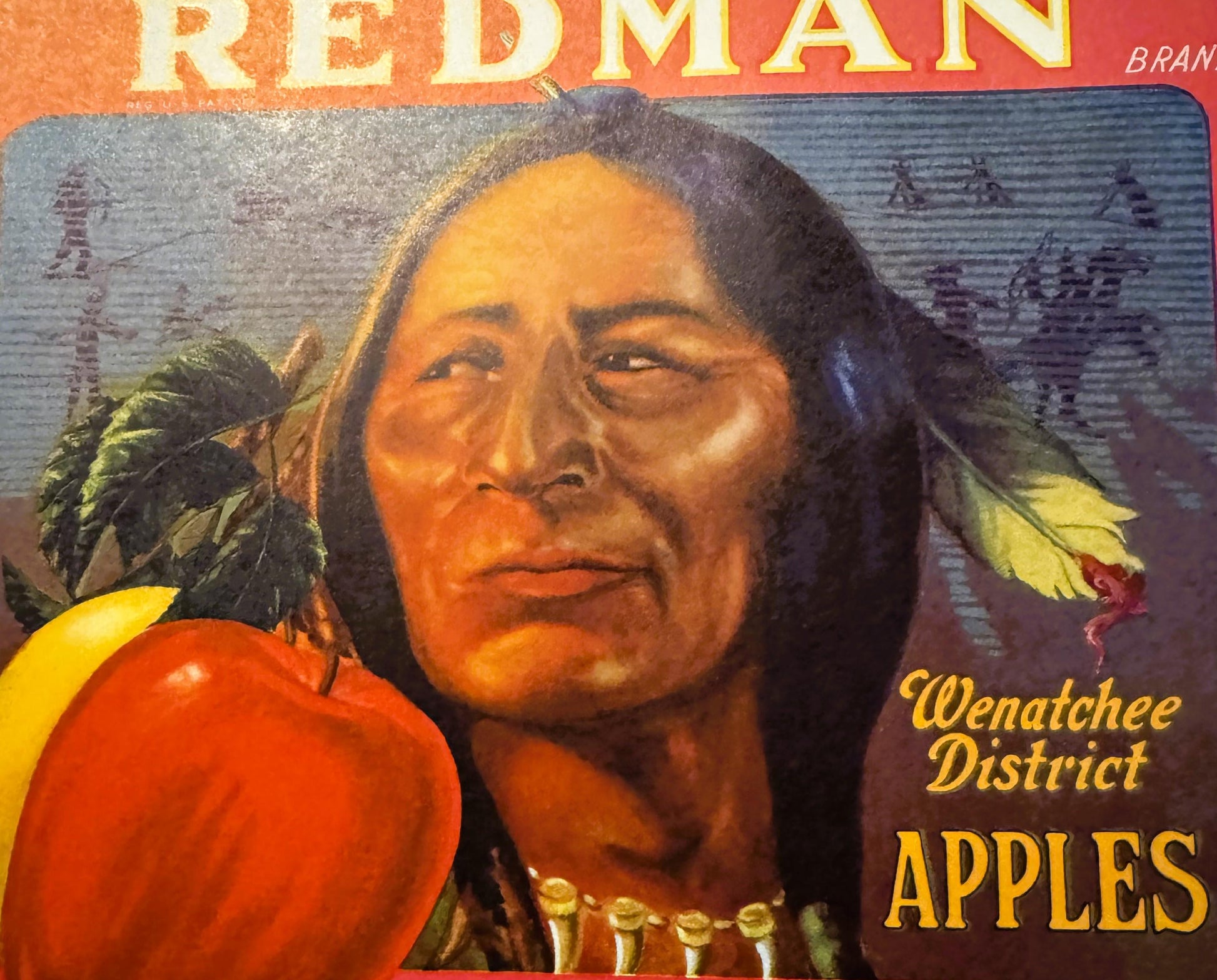 Vintage Redman Brand apple crate label featuring a Native American man with long hair and feathers, red apples, text reading 