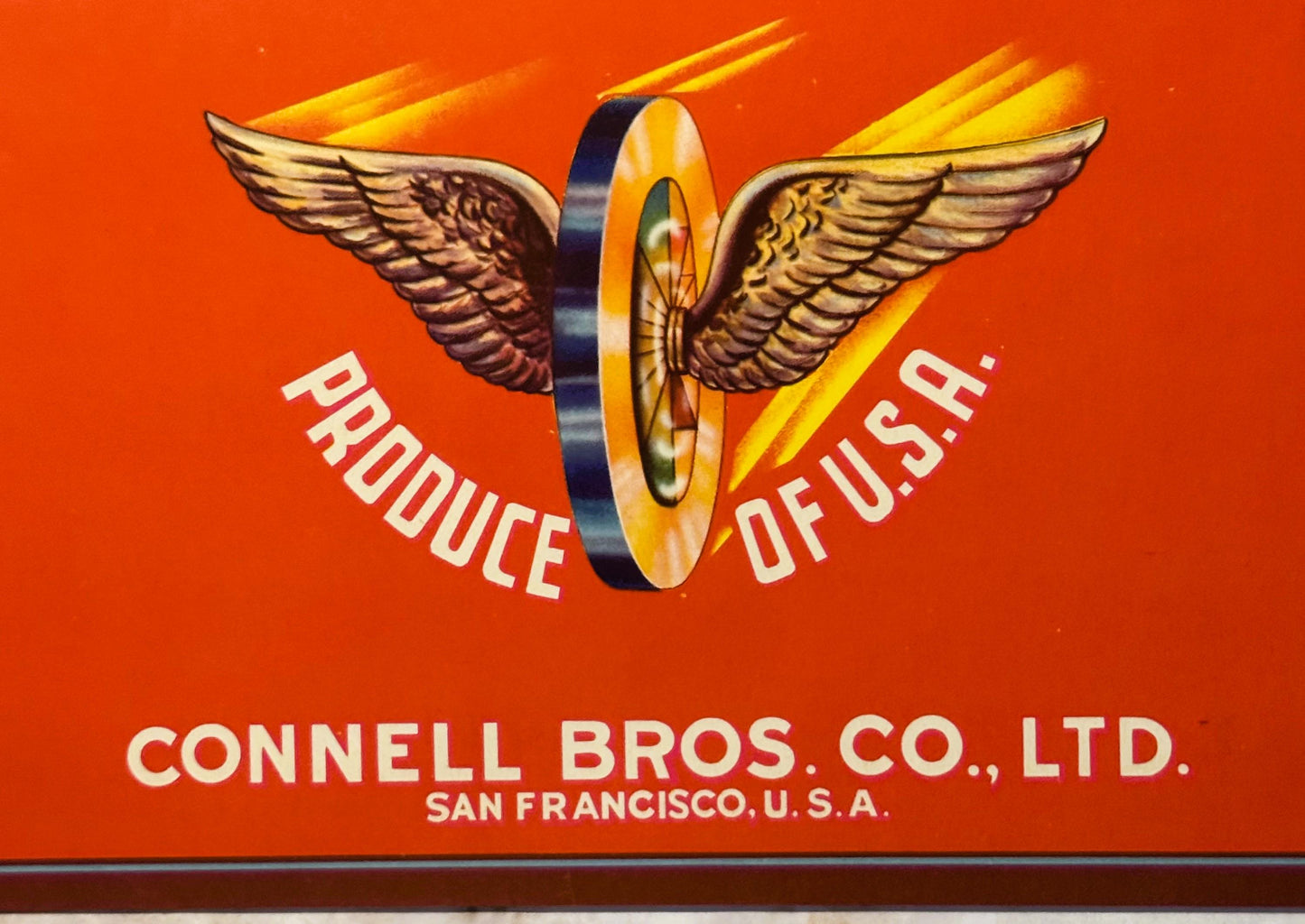 Vintage crate label with winged wheel logo, gold wings and blue center ring, "Produce of U.S.A." text, Connell Bros. Co. San 