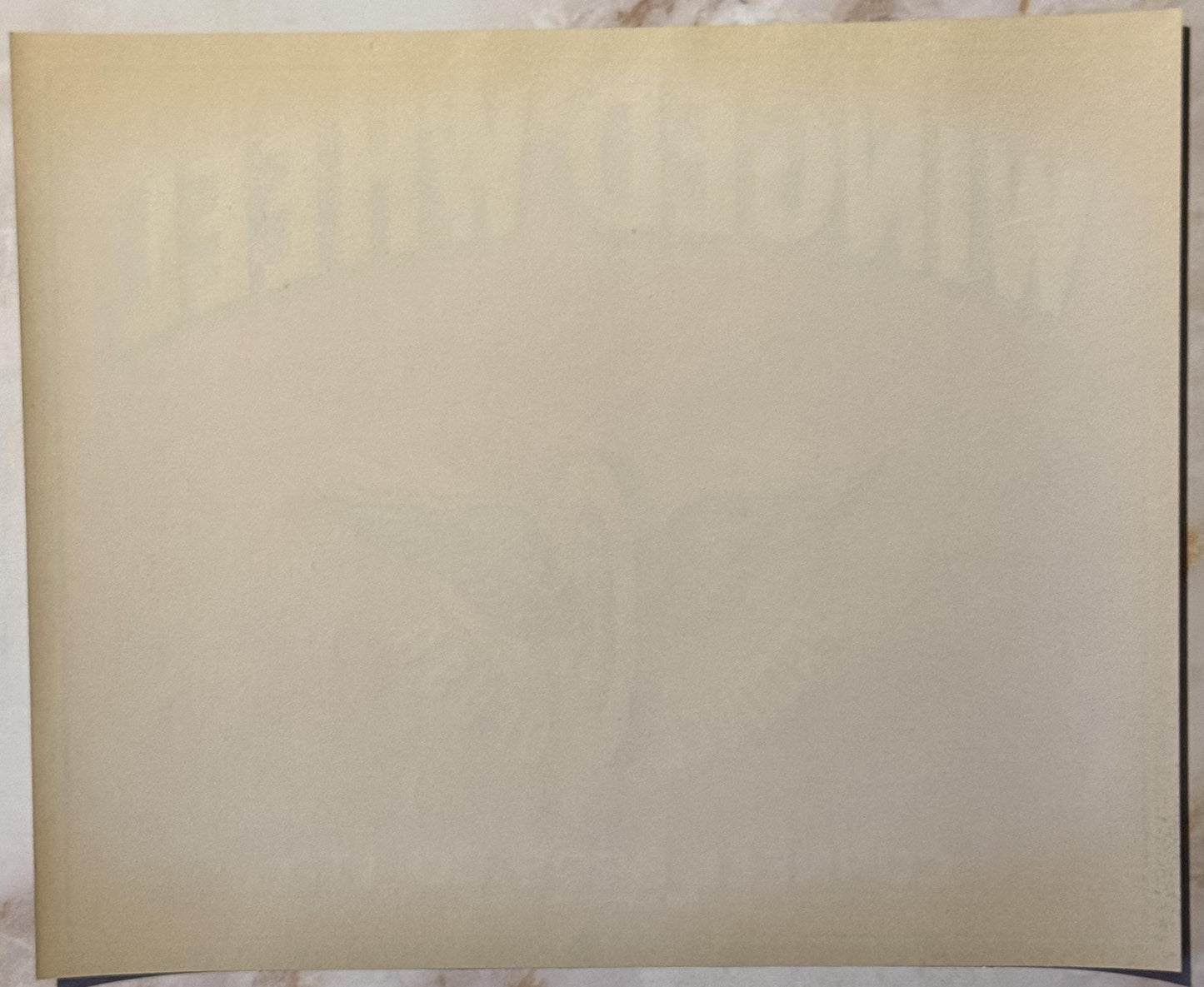 Blank cream-colored vintage crate label with curved bottom edge, photographed flat against white background