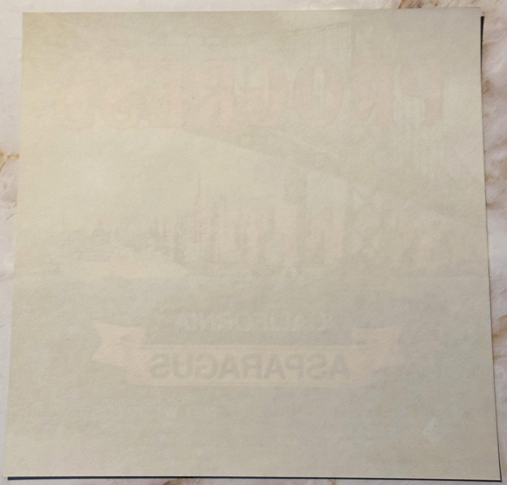 Cream-colored vintage crate label with faint embossed text, shown flat against white surface with dark border line visible at