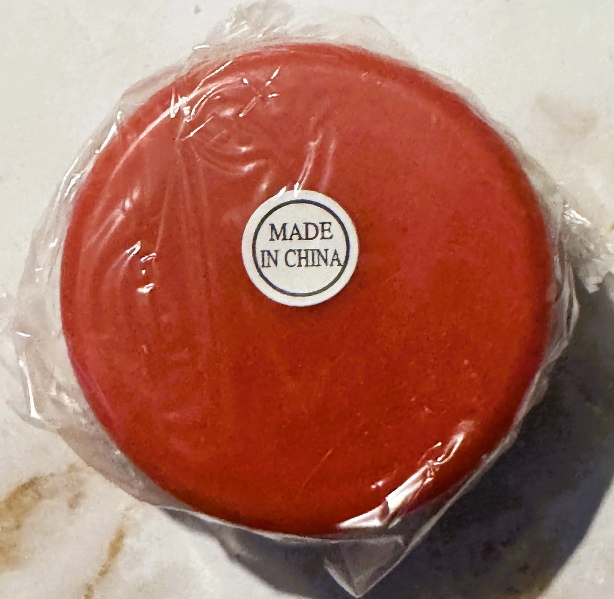 Red yo-yo in clear plastic packaging with "MADE IN CHINA" label visible, photographed from above on a light surface