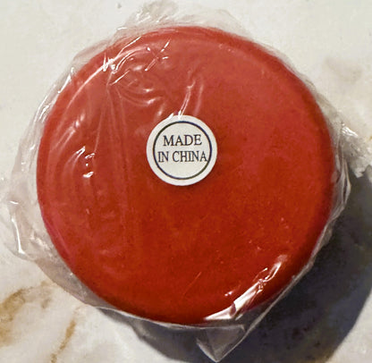 Red yo-yo in clear plastic packaging with "MADE IN CHINA" label visible, photographed from above on a light surface