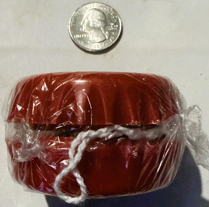 Red Coca-Cola bottle cap yo-yo in clear plastic packaging with white string, shown next to a quarter for scale