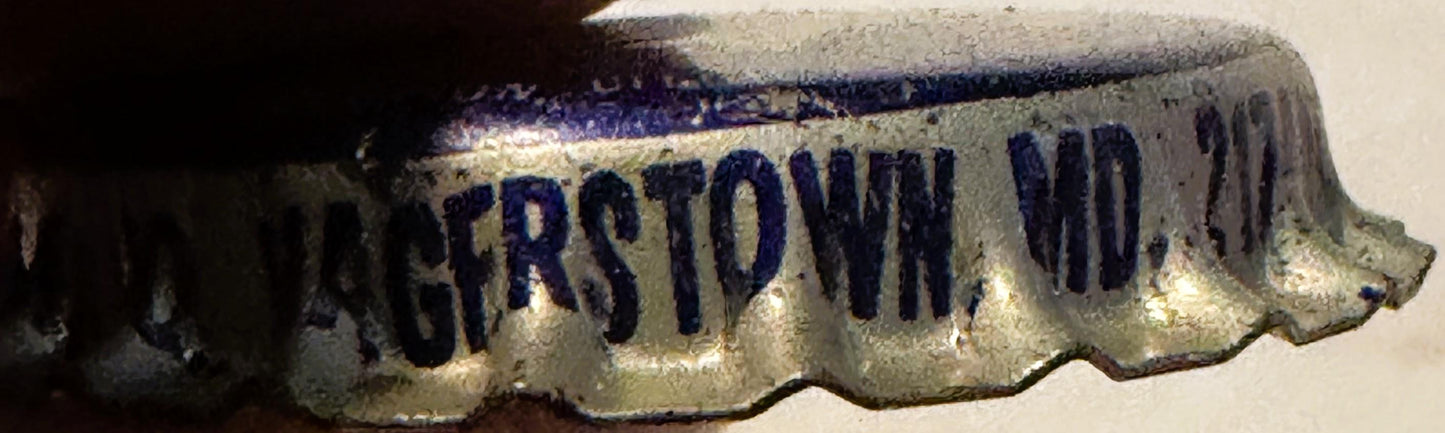 Vintage cream soda bottle cap with blue embossed text on cream background, shown at angle against white surface