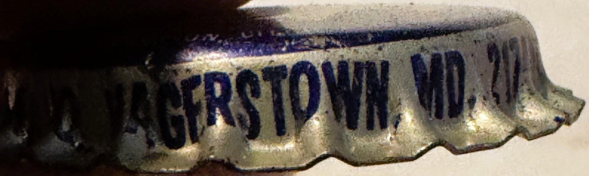 Vintage cream soda bottle cap with blue embossed text on cream background, shown at angle against white surface
