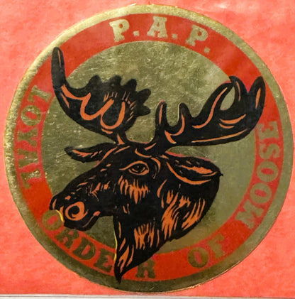 Circular emblem with black moose head outlined in orange on gray center, surrounded by red band with "R.A.P." at top and "LOY