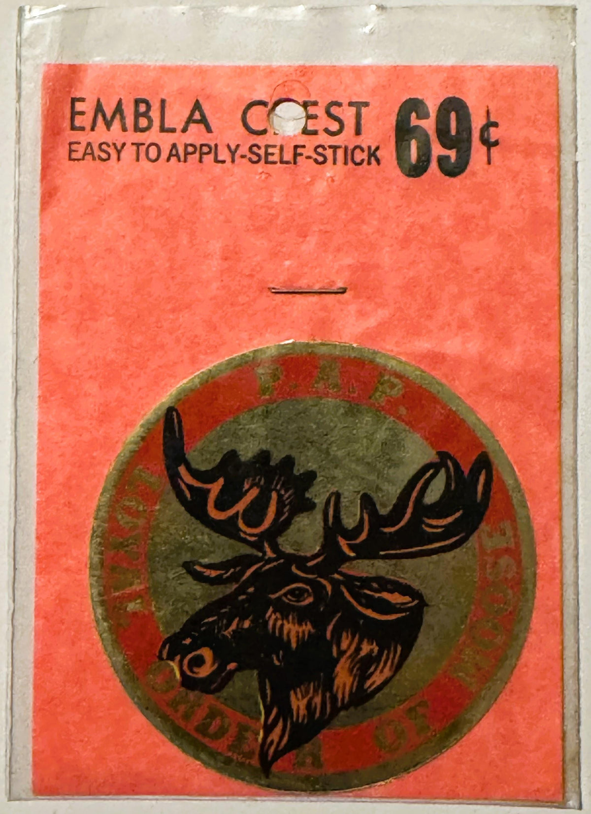 Vintage self-stick decal on red backing featuring moose head crest in black and orange, priced 69 cents, Embla Crest branding