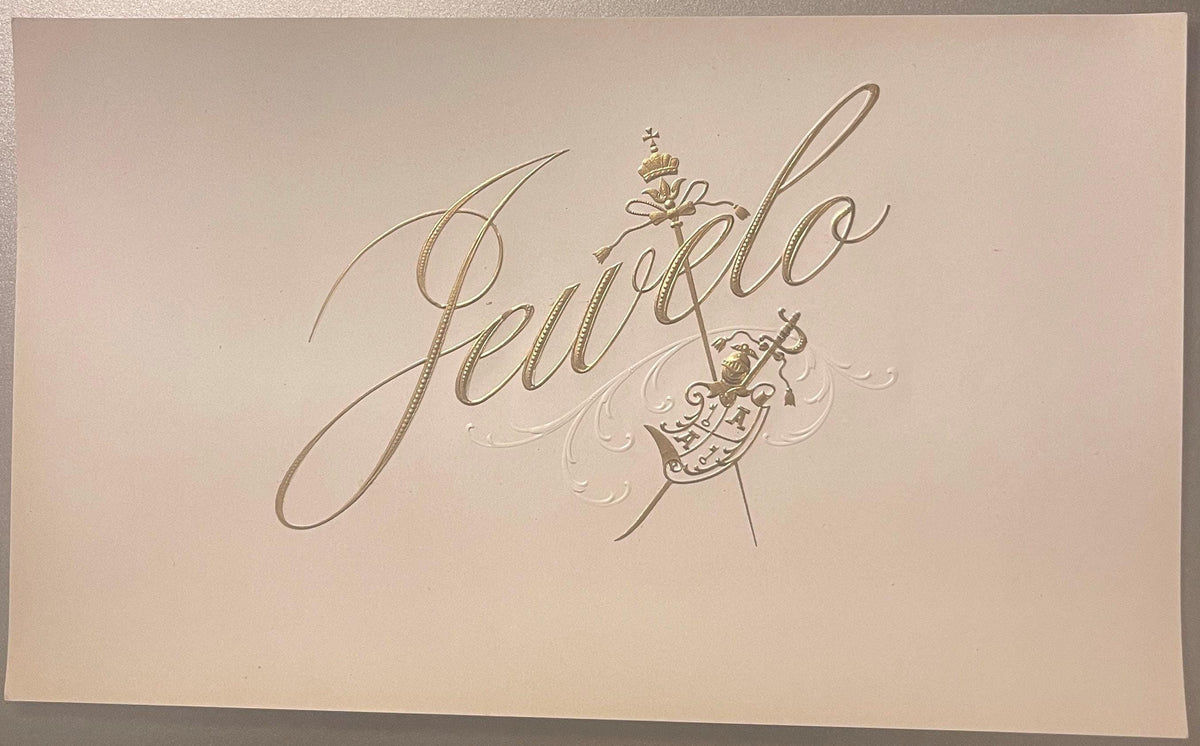 Gold embossed cigar label on cream cardstock reading "Jewelo" in flowing script with decorative coat of arms and ornamental f
