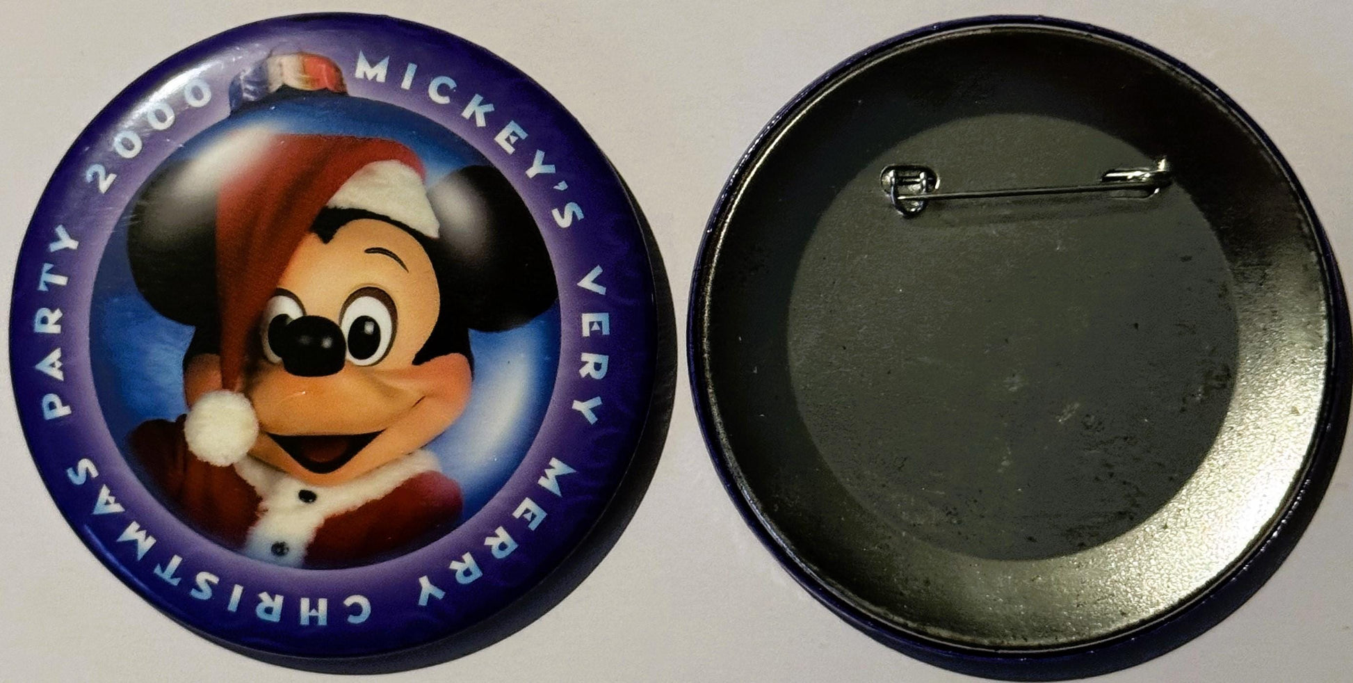 Front and back of circular Disney pin featuring Mickey Mouse in Santa hat with purple border text reading "2000 Mickey's Very
