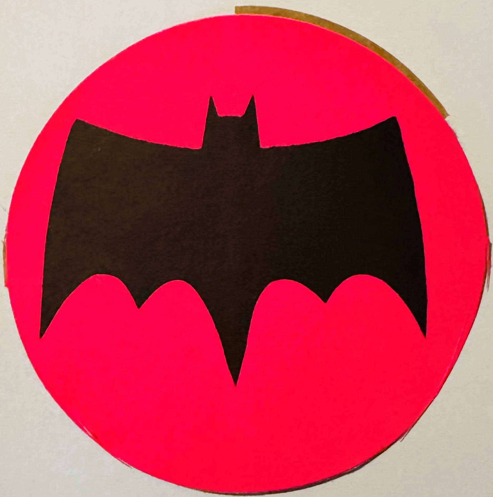 Black bat silhouette on bright pink circular background, vintage sticker or decal viewed flat against white surface