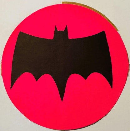Black bat silhouette on bright pink circular background, vintage sticker or decal viewed flat against white surface