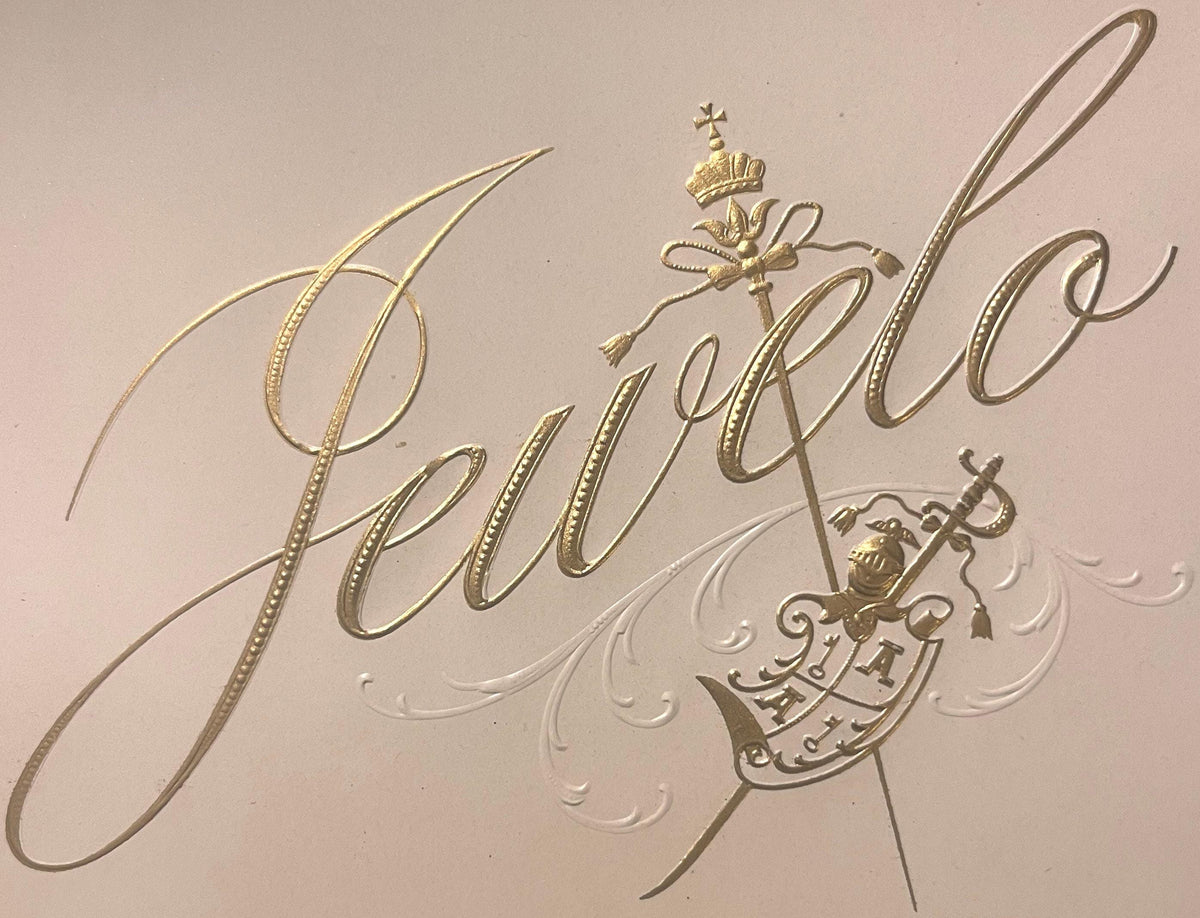 Gold embossed cigar label with "Jewelo" script text, crown and sword emblem, and ornamental flourishes on cream background