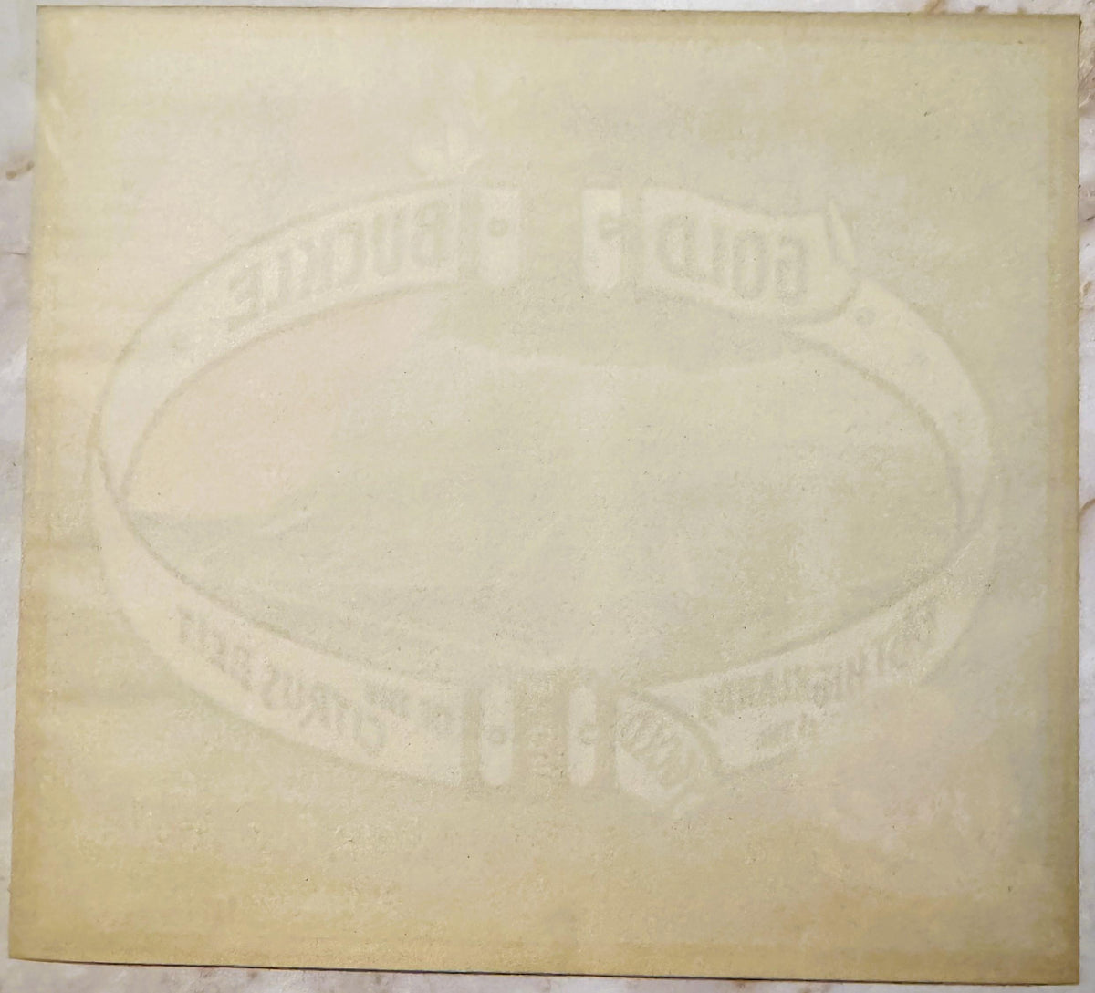 Cream-colored embossed fruit crate label with oval center design and text reading "Gold Buckle" and "Sunkist," photographed f