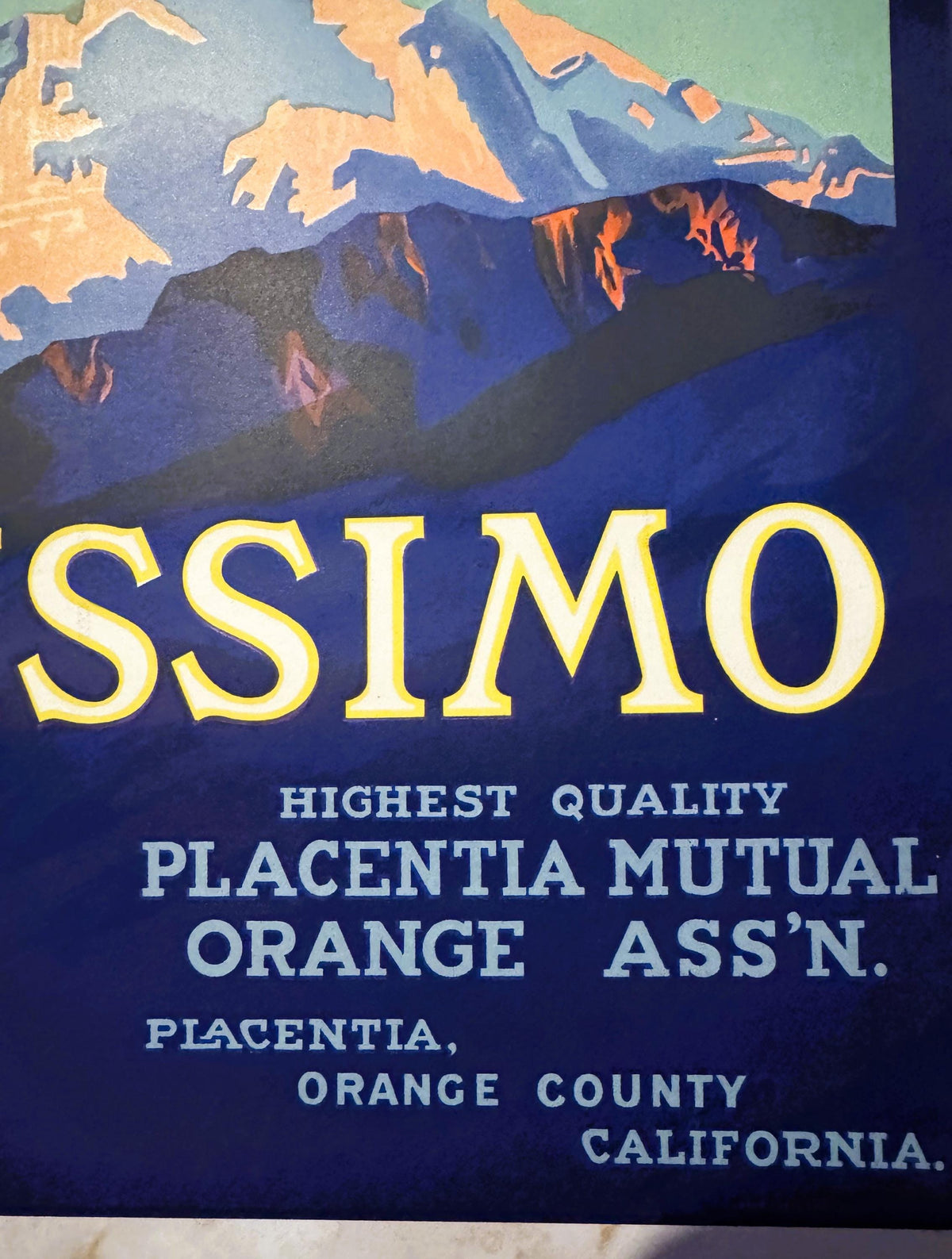 Close-up of the Altissimo crate label's right side: SSIMO in cream letters under the snowy mountains, then Highest Quality, Placentia Mutual Orange Ass'n., Placentia, Orange County, California on navy
