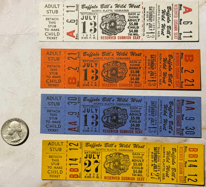Four vintage 1974 Buffalo Bill's Wild West show tickets in tan, orange, blue, and yellow with a quarter for scale