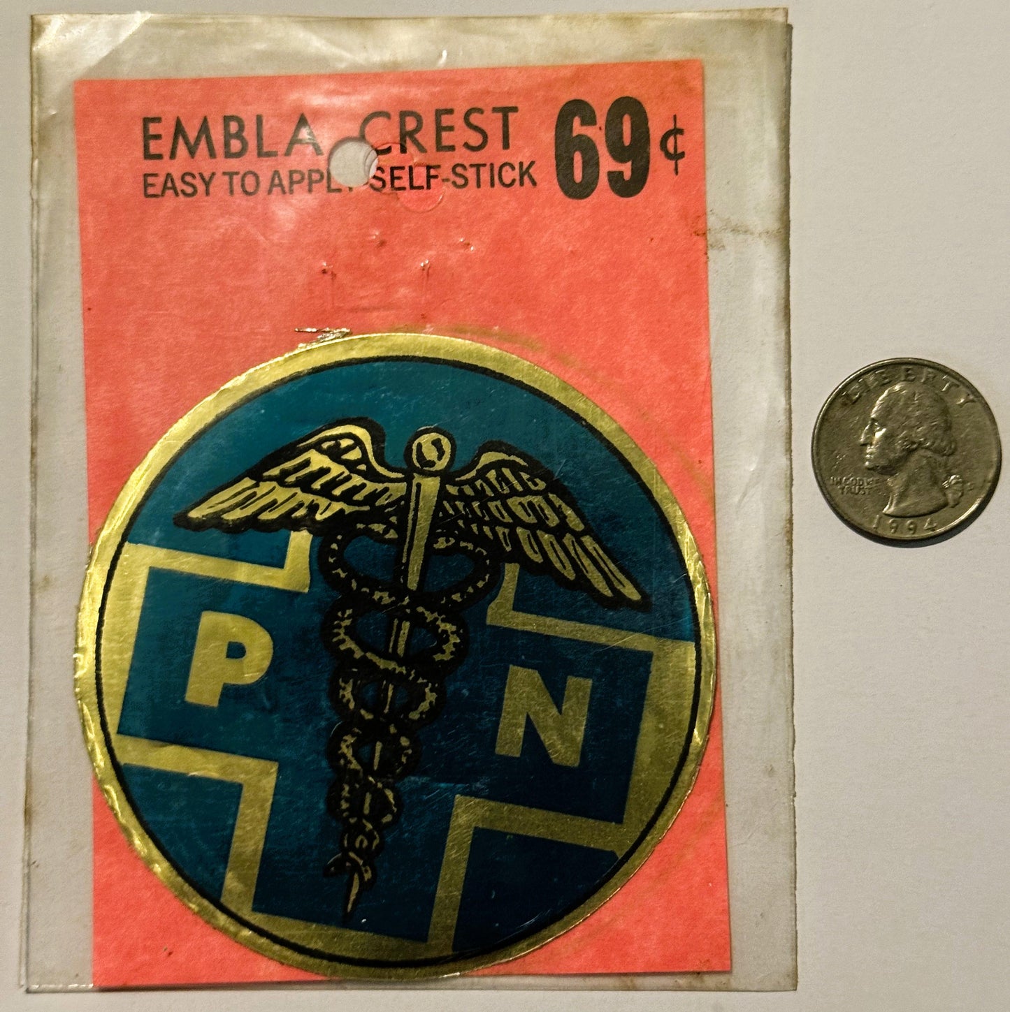 Vintage self-stick emblem crest decal priced 69¢, featuring winged caduceus and "RN" letters on blue and gold circular design