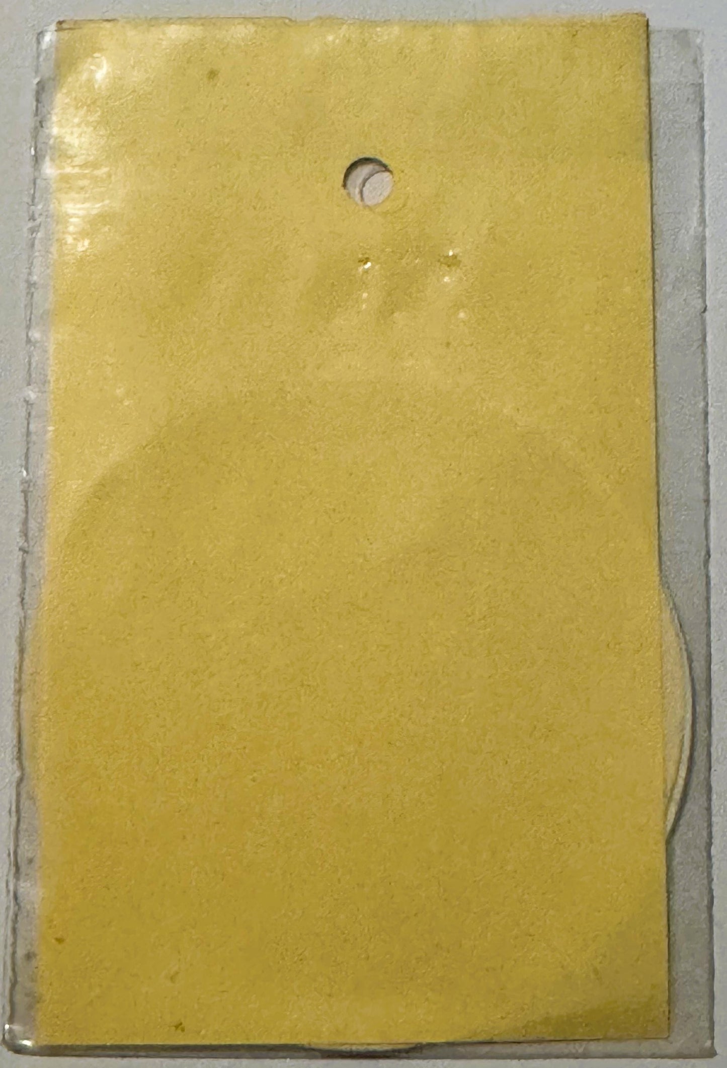 Yellow vintage decal with small circular hole at top, displayed against white backing card