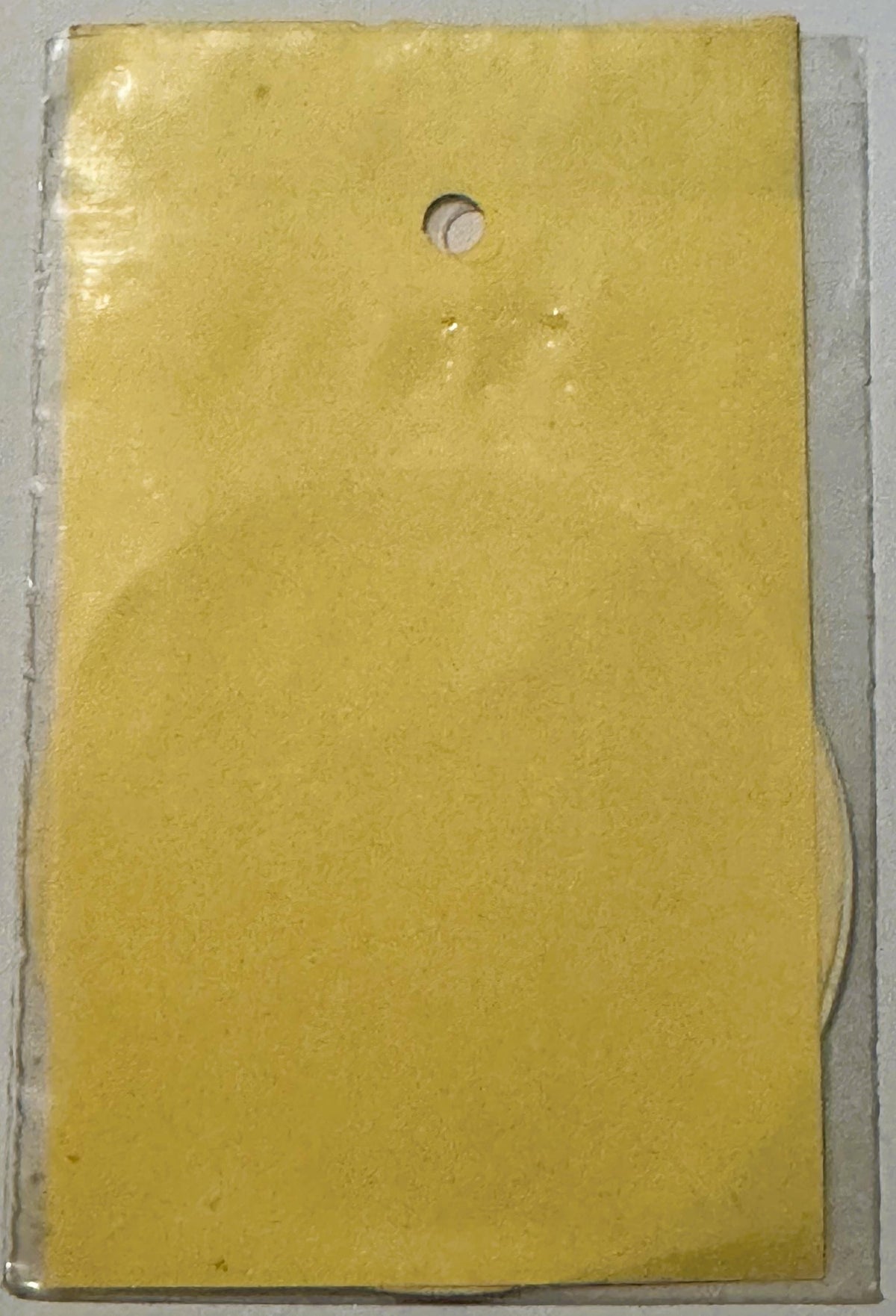 Yellow vintage decal with small circular hole at top, displayed against white backing card