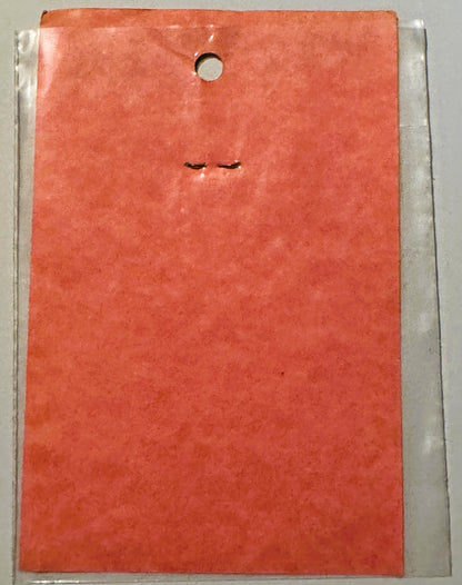 Coral-red vintage decal sticker in clear plastic package, showing minimalist closed eyes design, hung from hole at top