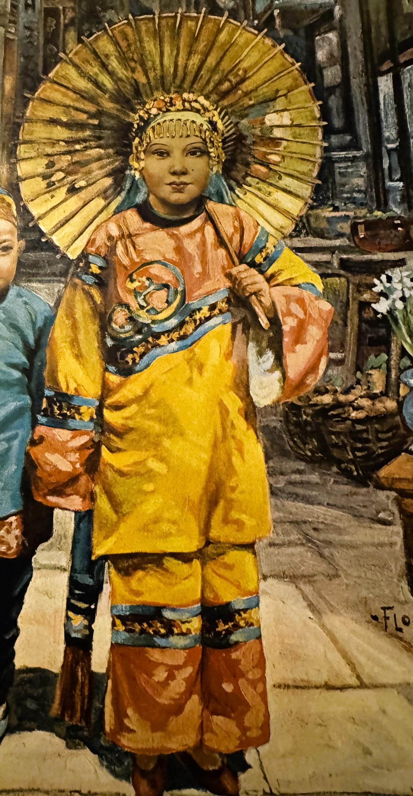 Colorful antique print of a young child in yellow silk robe with ornate gold halo headdress, standing in a street scene, sign
