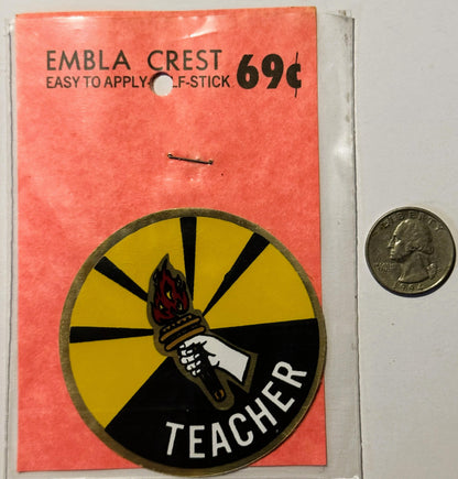 Vintage teacher decal on coral packaging showing torch emblem with yellow and black design, priced 69¢, displayed next to qua