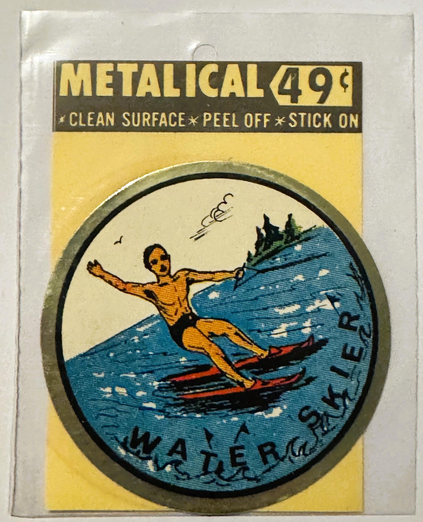 Unopened vintage water skier decal in yellow package with metallic border showing figure water skiing in blue water, priced a