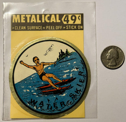 Unopened metallic water skier decal in yellow packaging next to a quarter for scale, showing orange figure skiing on blue wat
