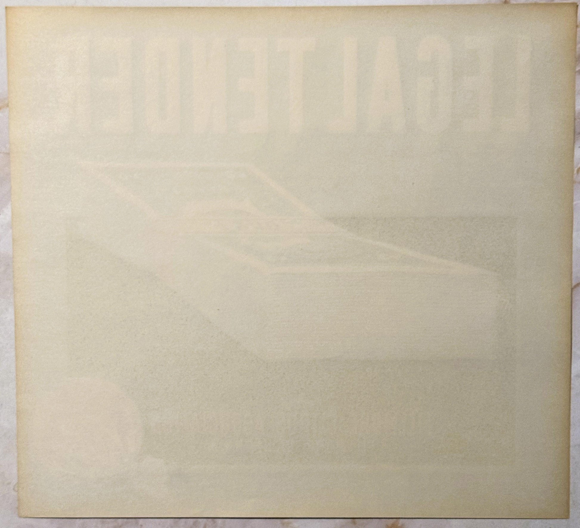Cream-colored vintage crate label with faint embossed or printed text, shown flat against white surface