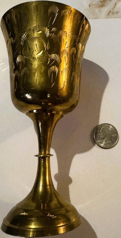 Brass goblet with etched floral design, shown upright next to a quarter for scale, casting a shadow on white surface