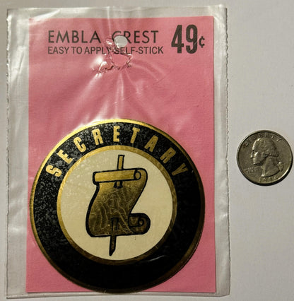 Unopened vintage Secretary self-stick emblem crest decal on pink card priced 49¢, shown next to quarter for scale