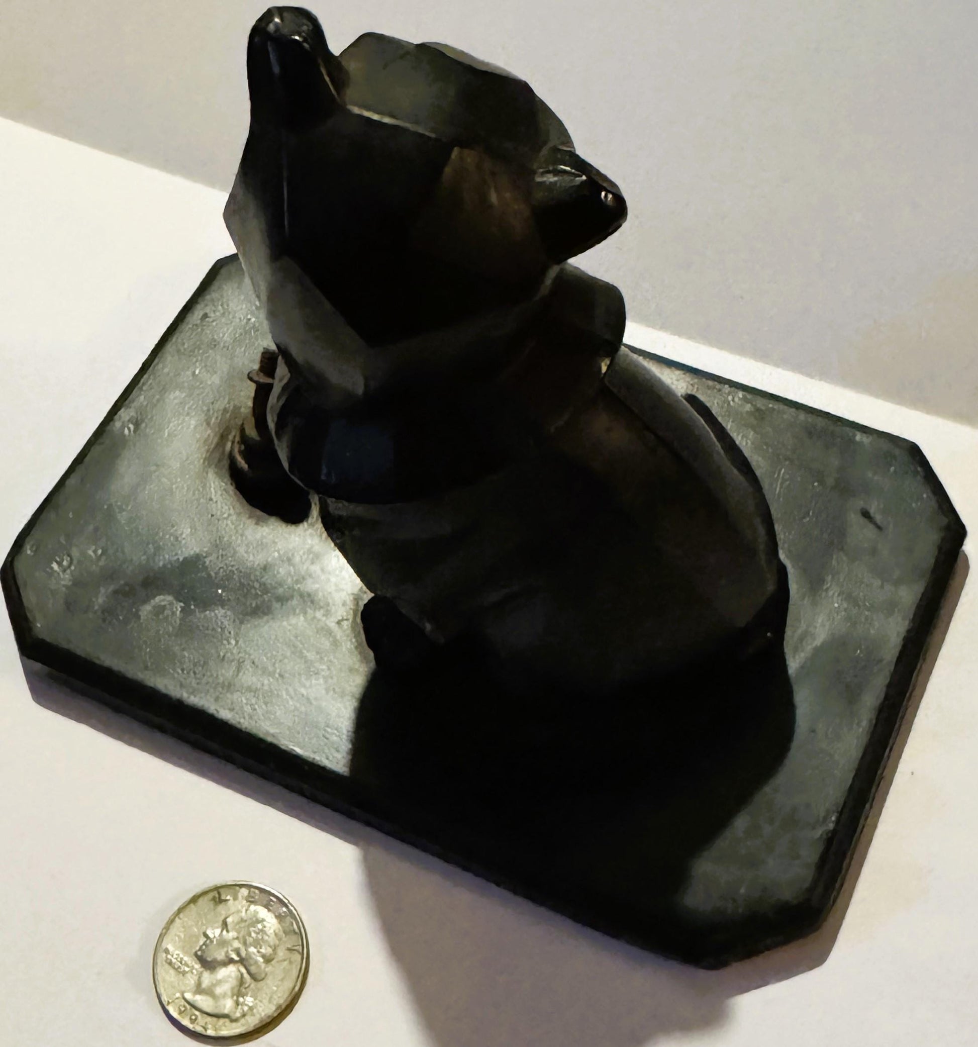 Black cast metal bulldog head inkwell on rectangular base, photographed from above with a quarter coin for scale