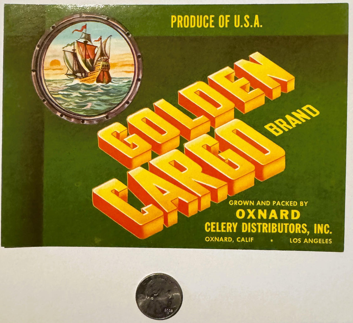 Vintage Golden Cargo celery crate label with yellow 3D letters, sailing ship porthole, green background, and quarter coin for