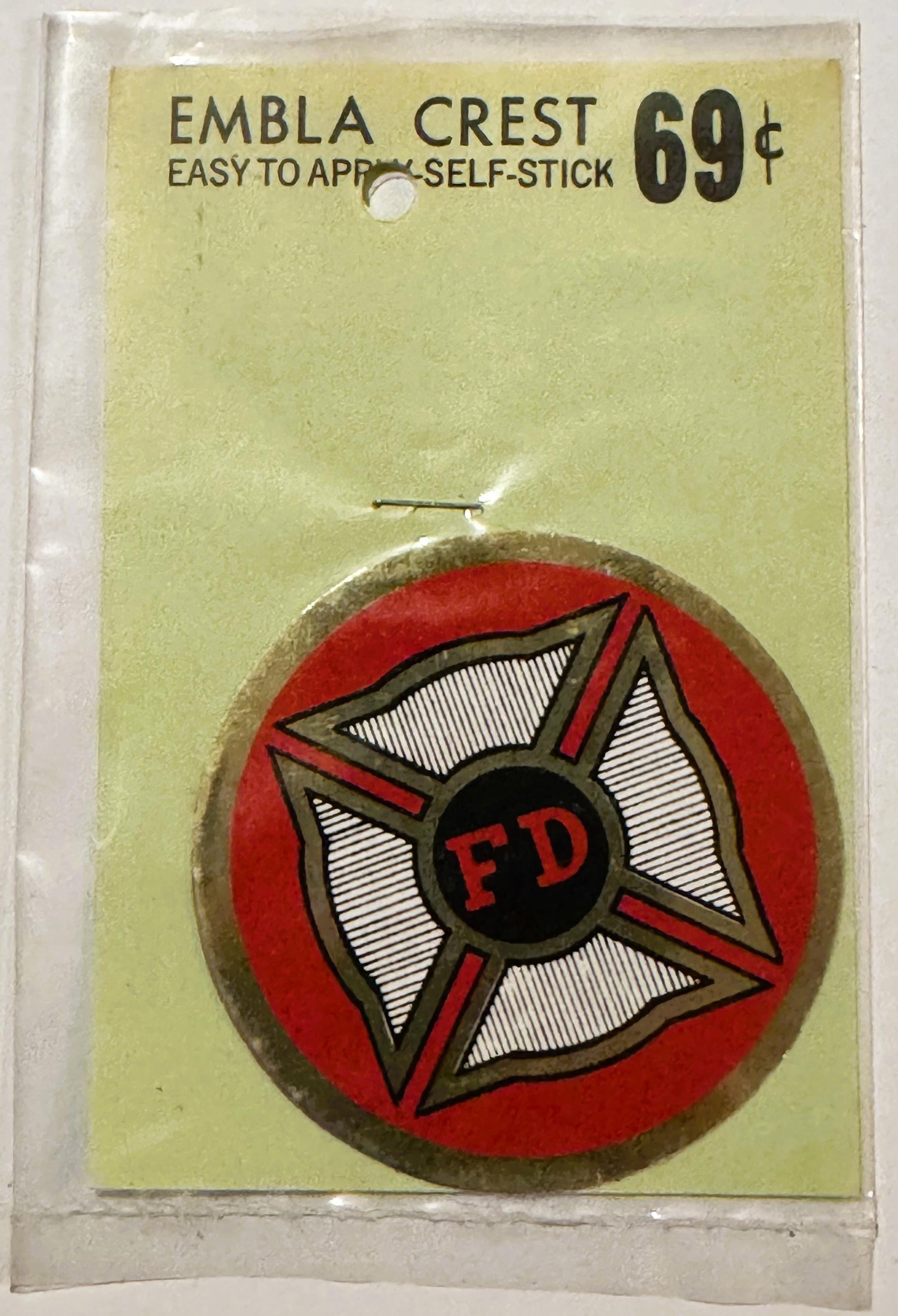 Vintage FD fire department self-stick emblem crest with red circular background, Maltese cross design, and tan border on yell
