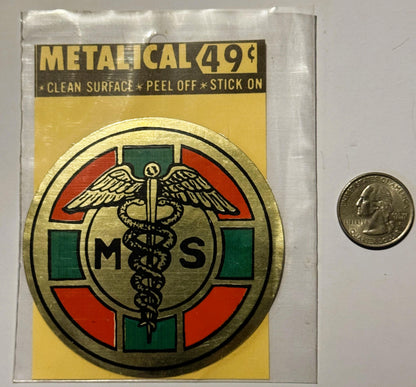 Metallic medical caduceus sticker in original packaging with quarter for scale, showing winged staff symbol with "MS" letters