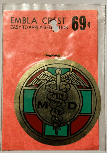Vintage medical emblem decal on orange backing card showing caduceus symbol with "MD" text and green/red colored sections, pr