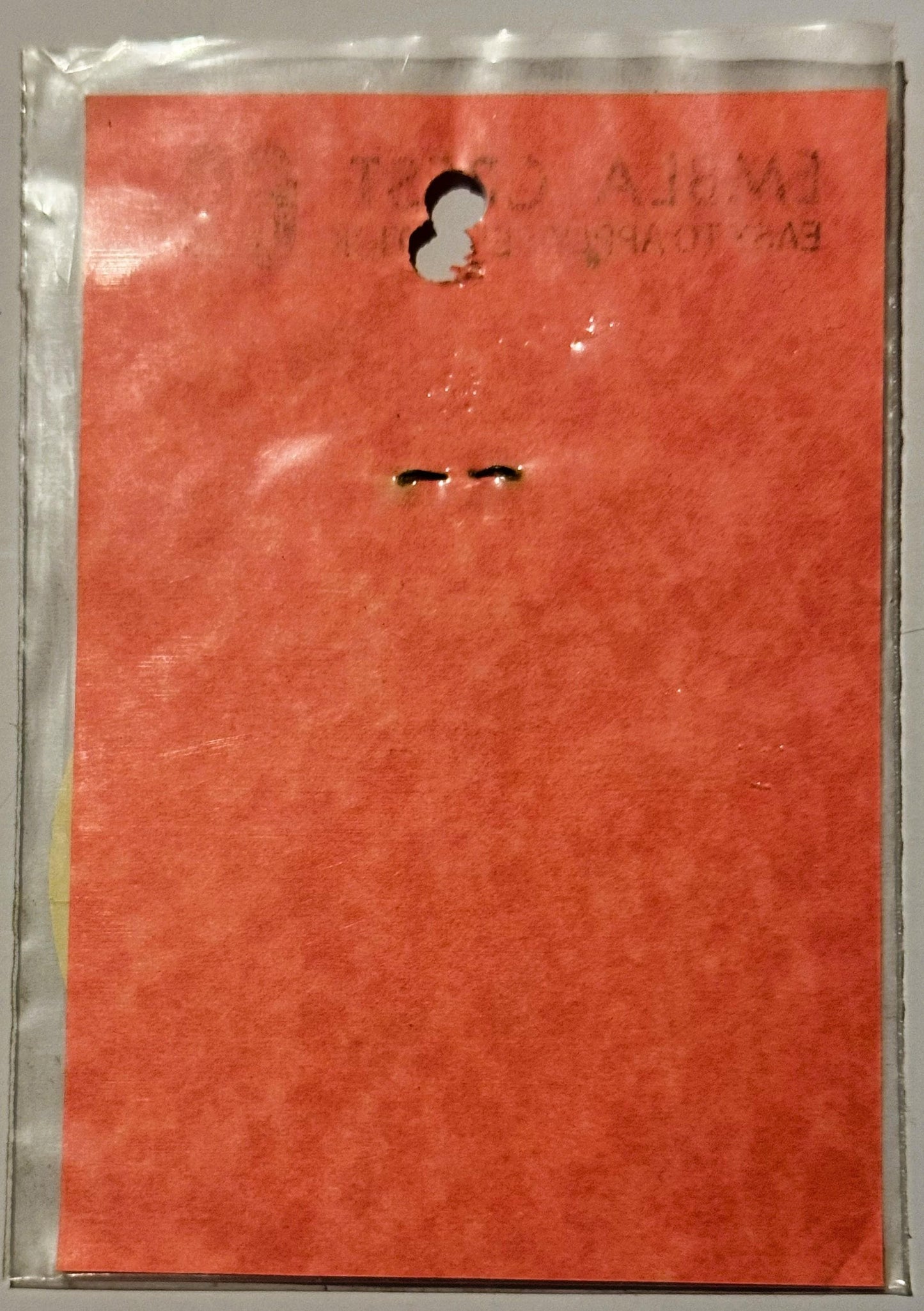 Bright red vintage decal in clear plastic sleeve showing minimalist face with two dots for eyes and curved line, with hole-pu