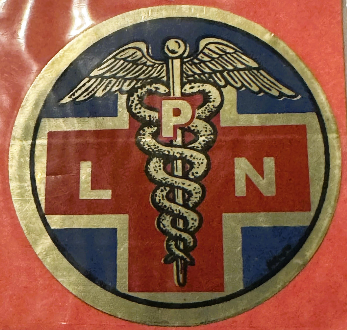 Circular medical decal with caduceus symbol centered on red cross, surrounded by blue and tan sections with "LPN" letters on 
