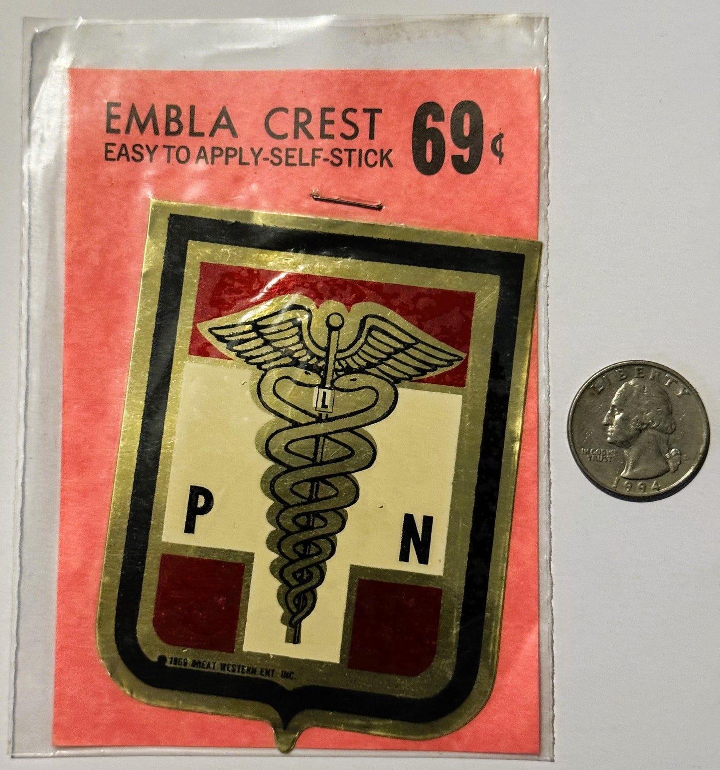 Vintage self-stick emblem crest priced at 69 cents, featuring caduceus medical symbol with P and N letters, displayed next to