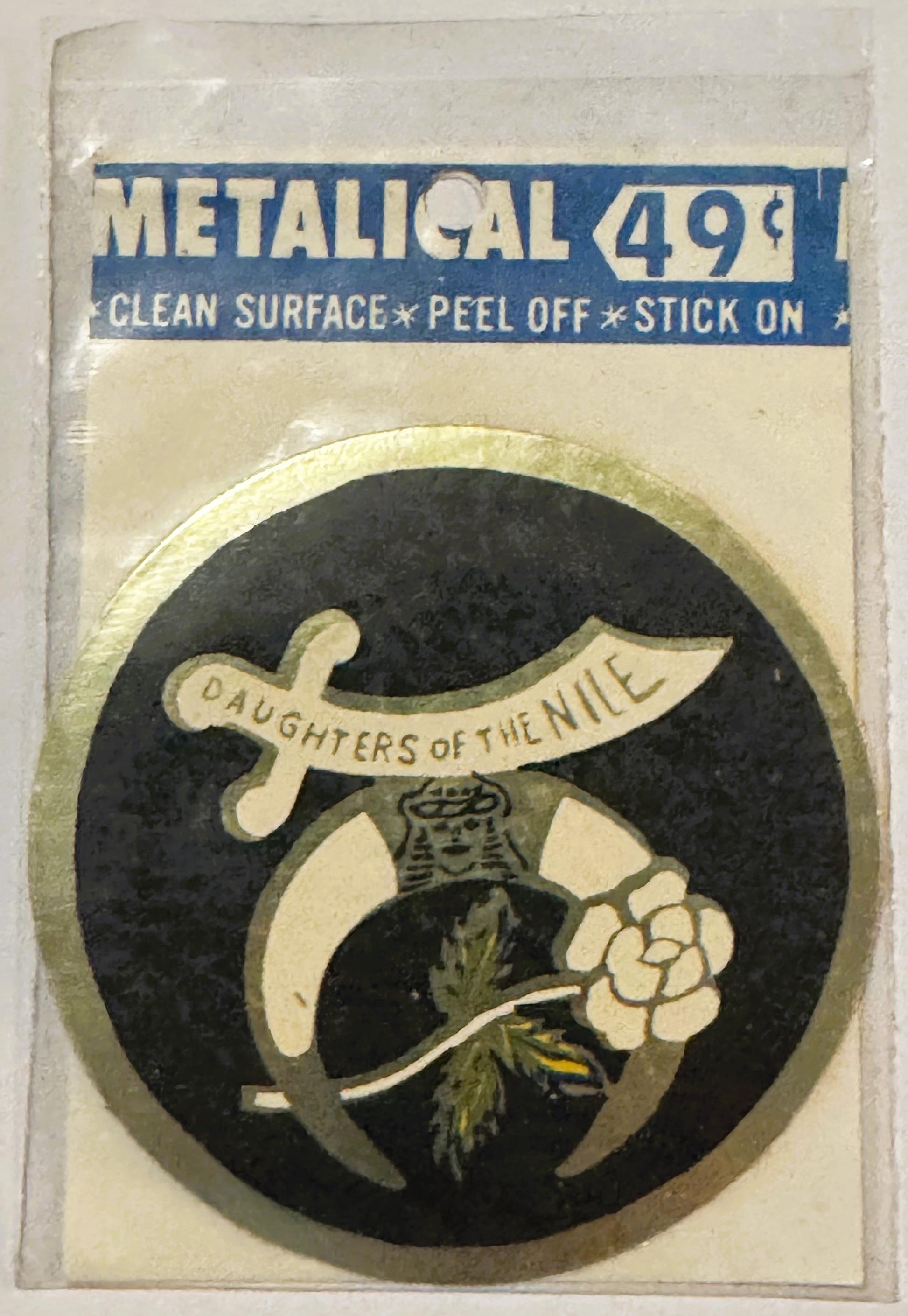 Vintage metallic decal sticker in original packaging showing "Daughters of the Nile" emblem with curved sword and flower on d