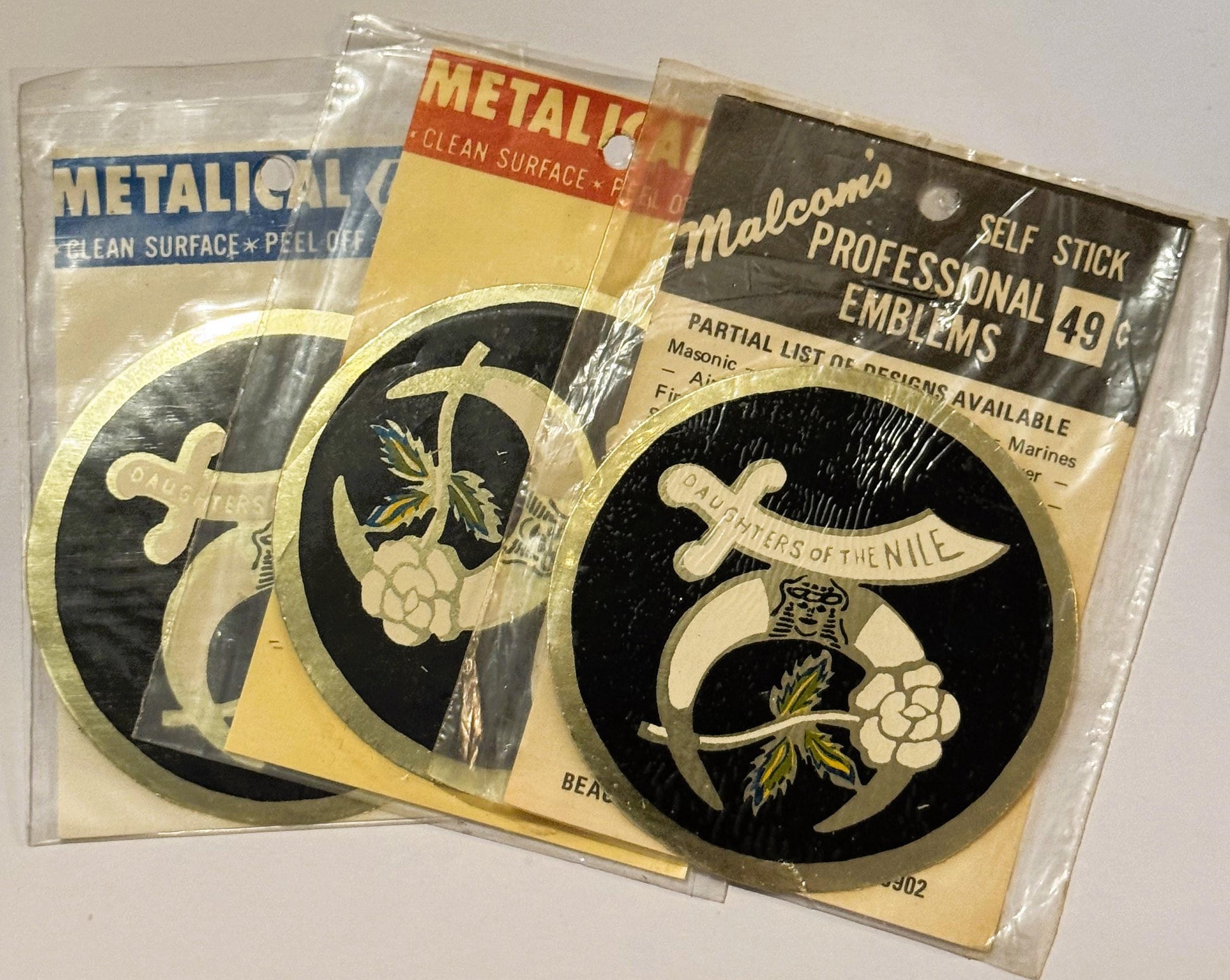 Three vintage self-stick emblems featuring "Daughters of the Nile" circular black and gold designs with crescent moons and lo
